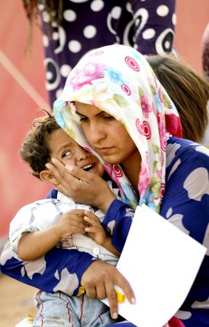 Uma refugiada síria consola seu filho na fronteira com a Turquia.